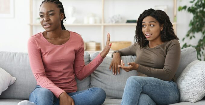 Annoyed woman showing stop gesture to her scolding girlfriend