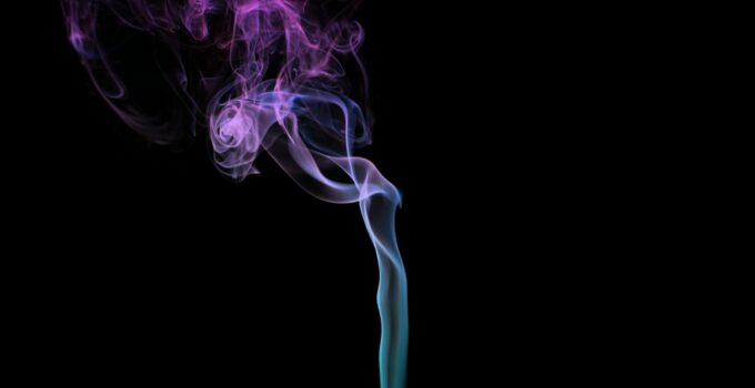 Multicolored smoke for aromatherapy relaxation on black background, beautiful swirled puffs of smoke