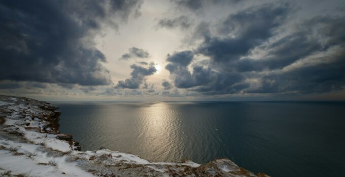 Seacoast in the snow, under heaven with clouds